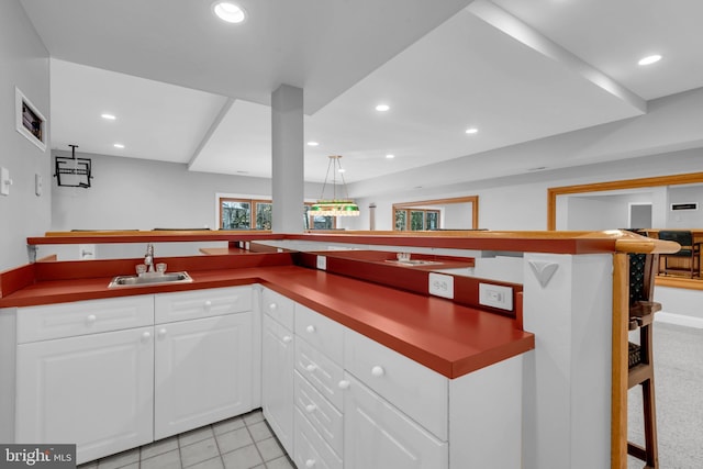 kitchen with kitchen peninsula, white cabinets, and sink