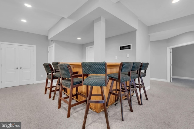 dining area with indoor bar and light colored carpet