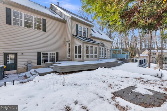 snow covered house with a wooden deck