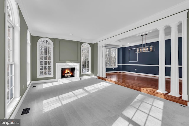 unfurnished living room featuring carpet, crown molding, and decorative columns