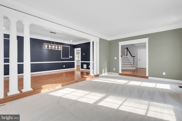 unfurnished living room with decorative columns, carpet, crown molding, and a notable chandelier