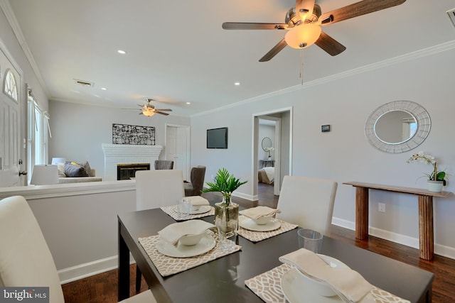 dining space featuring a brick fireplace, ceiling fan, crown molding, and dark hardwood / wood-style floors