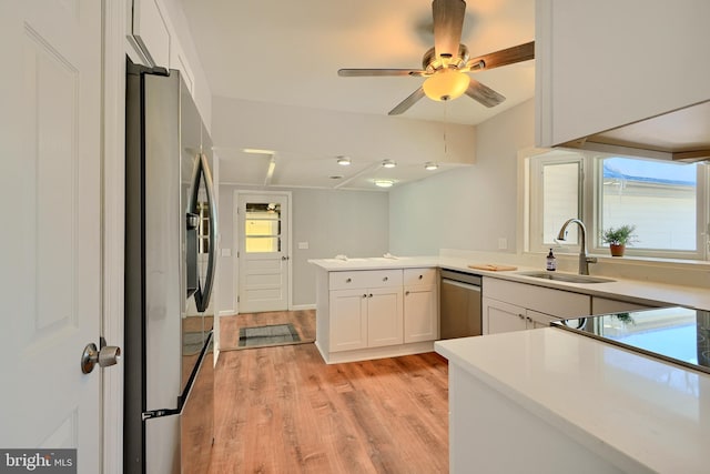 kitchen featuring stainless steel appliances, kitchen peninsula, white cabinets, light hardwood / wood-style flooring, and sink