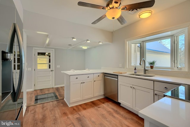 kitchen featuring kitchen peninsula, light hardwood / wood-style floors, white cabinetry, appliances with stainless steel finishes, and sink