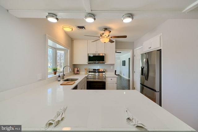 kitchen featuring stainless steel appliances, sink, white cabinets, ceiling fan, and kitchen peninsula