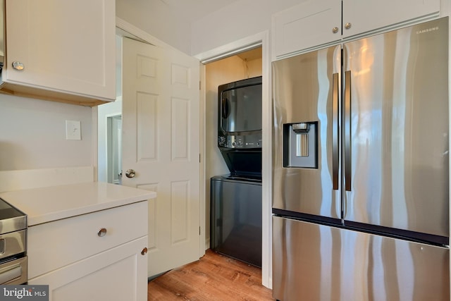 kitchen with stacked washing maching and dryer, white cabinetry, stainless steel fridge with ice dispenser, and light hardwood / wood-style flooring