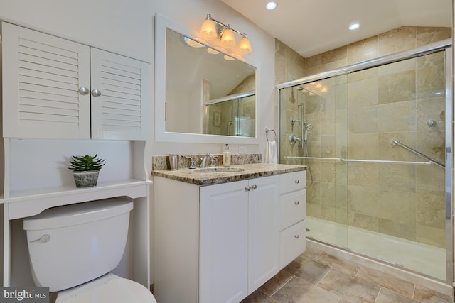 bathroom featuring toilet, vaulted ceiling, a shower with shower door, and vanity