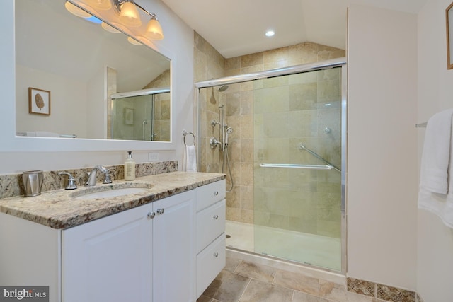 bathroom featuring a shower with shower door and vanity