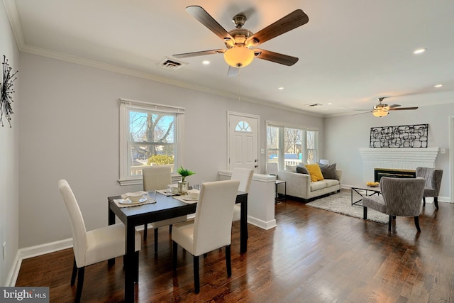 dining room with a brick fireplace, ceiling fan, ornamental molding, and plenty of natural light