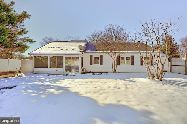 snow covered back of property with a sunroom