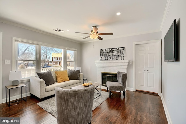 living room with a fireplace, dark wood-type flooring, ceiling fan, and ornamental molding