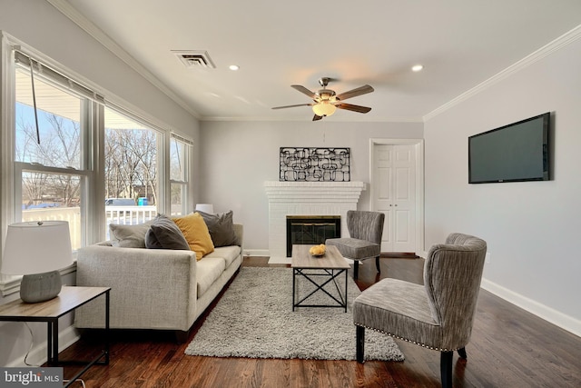 living room featuring ceiling fan, dark hardwood / wood-style flooring, crown molding, and a fireplace