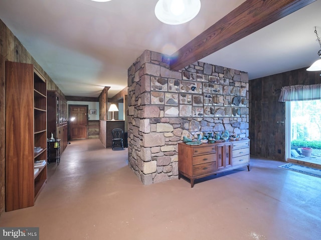 unfurnished living room featuring beam ceiling, concrete floors, and wood walls