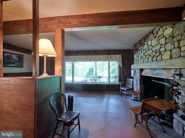 living room featuring a fireplace, beam ceiling, and wooden walls