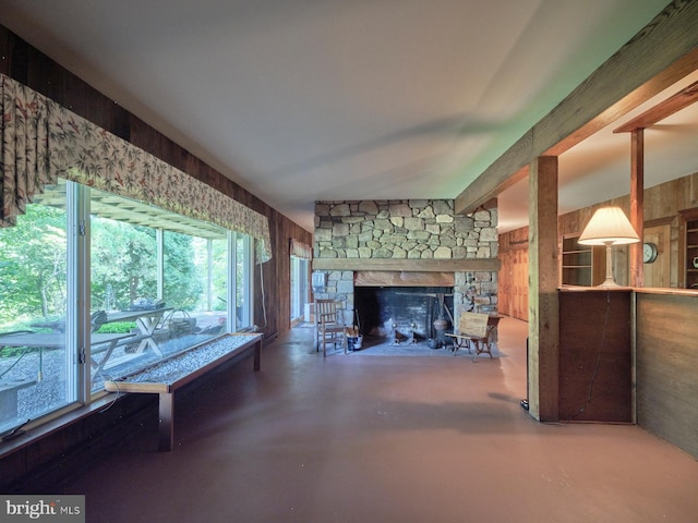 unfurnished living room featuring a stone fireplace and concrete flooring