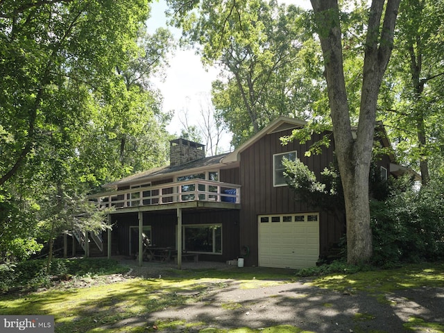 back of house featuring a garage and a wooden deck