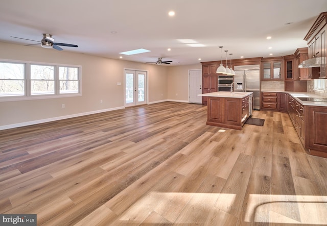 kitchen featuring appliances with stainless steel finishes, french doors, a skylight, a kitchen island, and hanging light fixtures