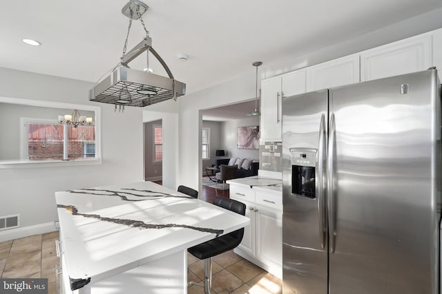 kitchen with decorative light fixtures, a notable chandelier, a center island, white cabinetry, and stainless steel fridge