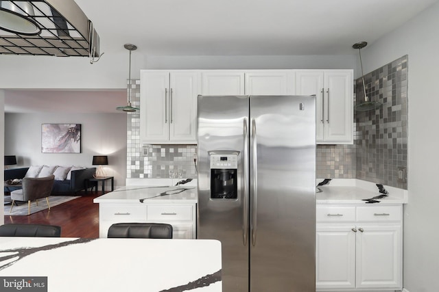 kitchen featuring white cabinets, stainless steel refrigerator with ice dispenser, backsplash, and pendant lighting