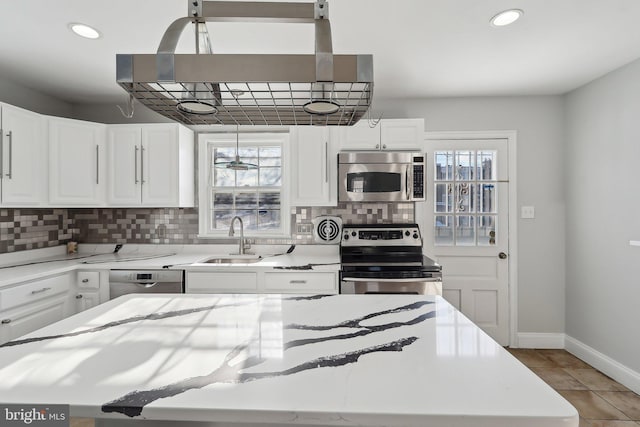 kitchen with appliances with stainless steel finishes, white cabinetry, tasteful backsplash, and sink