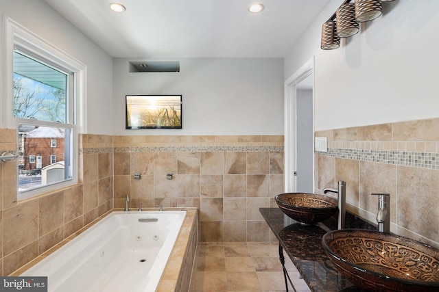 bathroom featuring tile walls, sink, and a relaxing tiled tub