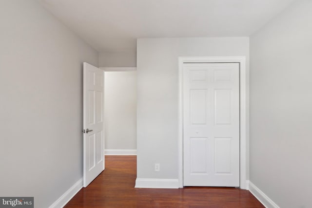 unfurnished bedroom with a closet and dark hardwood / wood-style flooring