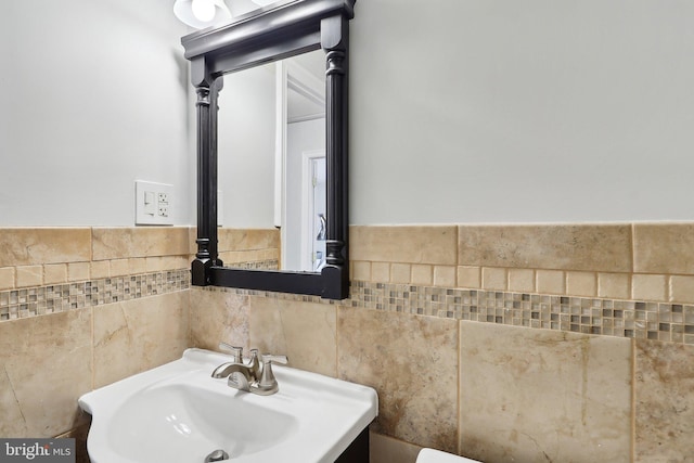 bathroom featuring sink and tile walls