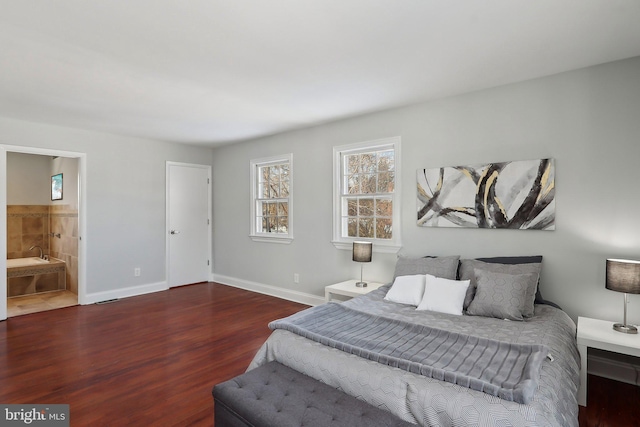 bedroom with ensuite bathroom and dark wood-type flooring