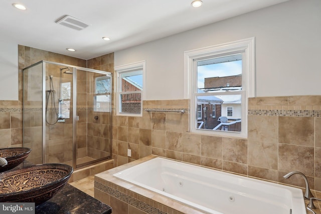 bathroom featuring shower with separate bathtub and tile walls