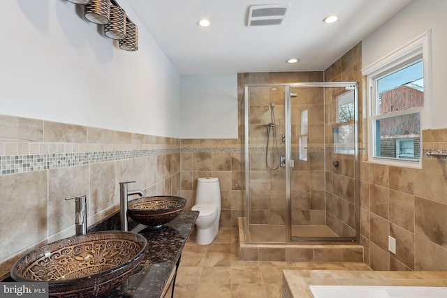 bathroom featuring toilet, tile walls, an enclosed shower, and sink