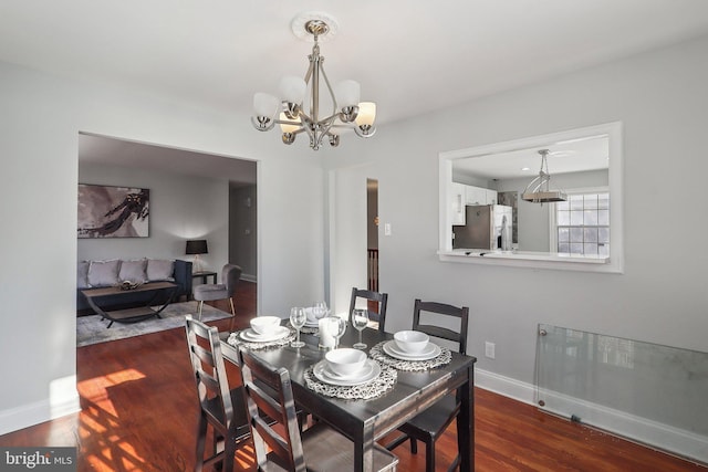 dining space with dark wood-type flooring and an inviting chandelier