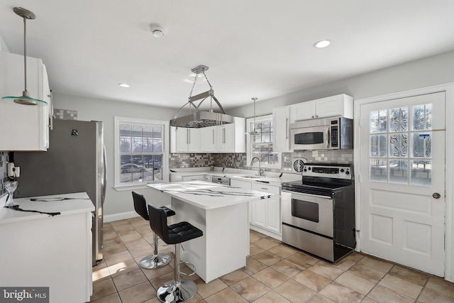 kitchen featuring white cabinets, a center island, decorative light fixtures, stainless steel appliances, and tasteful backsplash