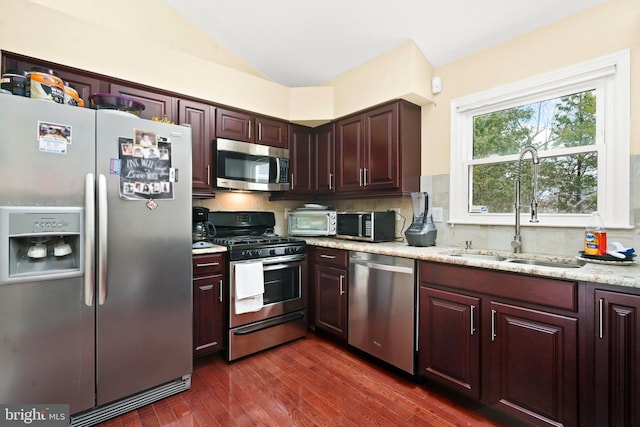 kitchen featuring sink, stainless steel appliances, tasteful backsplash, light stone counters, and dark hardwood / wood-style flooring