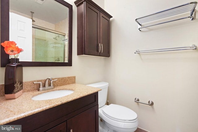 bathroom with vanity, toilet, and a shower with shower door