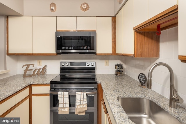 kitchen featuring sink, white cabinetry, stainless steel appliances, tasteful backsplash, and light stone counters