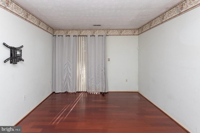 empty room with dark wood-type flooring and a textured ceiling