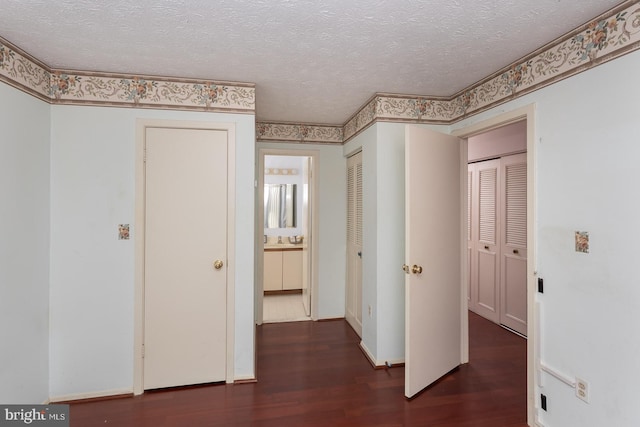 hallway with dark hardwood / wood-style flooring and a textured ceiling