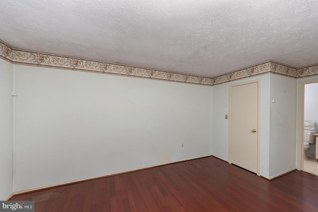 spare room with dark wood-type flooring and a textured ceiling