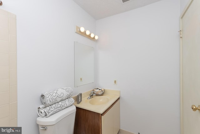 bathroom with vanity, toilet, and a textured ceiling