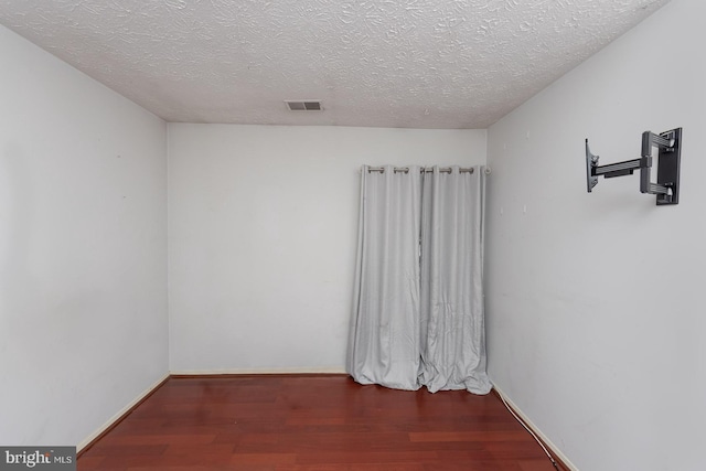 spare room featuring dark hardwood / wood-style flooring and a textured ceiling