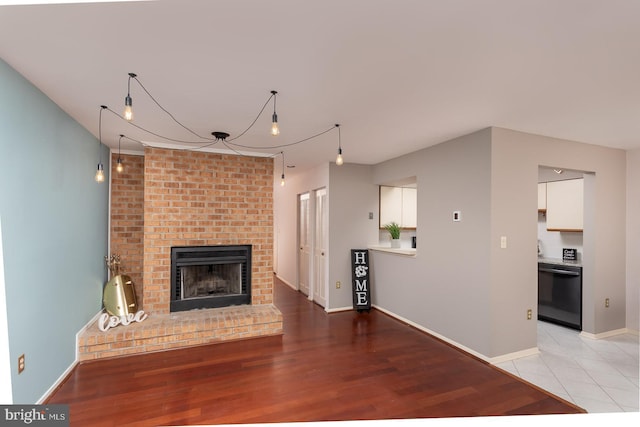 unfurnished living room with a brick fireplace and light wood-type flooring