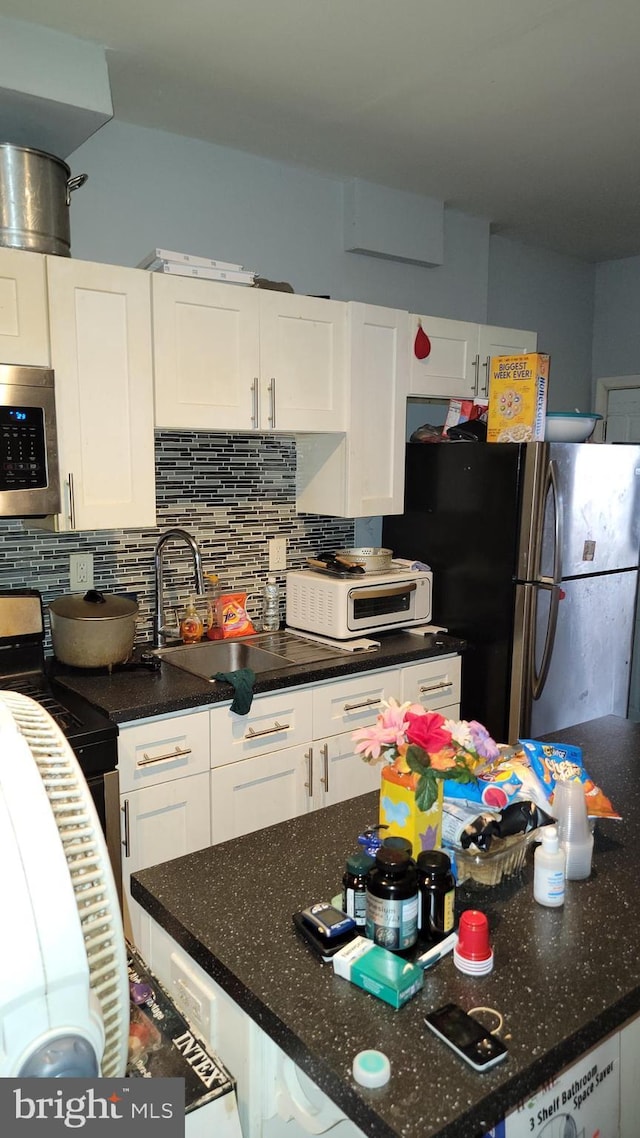 kitchen with backsplash, white cabinets, and stainless steel appliances