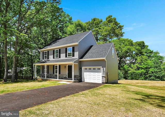 colonial inspired home with a porch, a garage, and a front yard