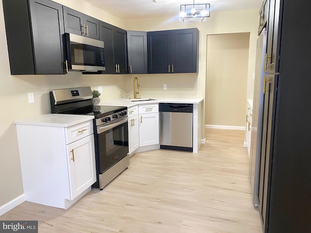 kitchen with sink, white cabinets, stainless steel appliances, and light hardwood / wood-style flooring