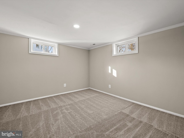 basement with ornamental molding, a wealth of natural light, and carpet