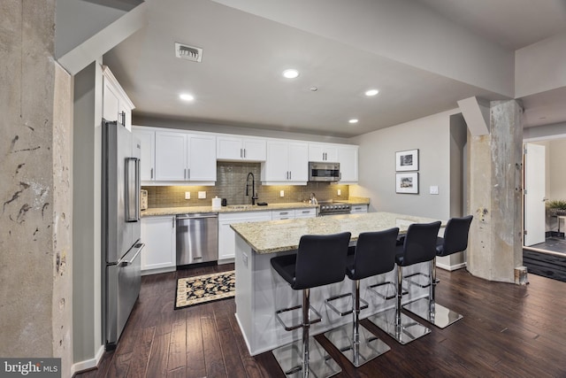 kitchen featuring light stone counters, a center island, white cabinets, and stainless steel appliances