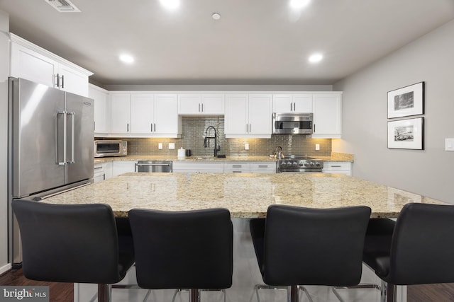 kitchen with a kitchen island, white cabinetry, sink, and appliances with stainless steel finishes