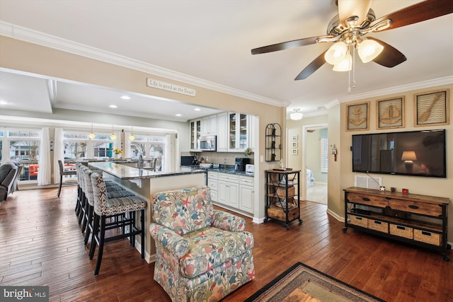 living room featuring ceiling fan, dark wood-type flooring, and crown molding