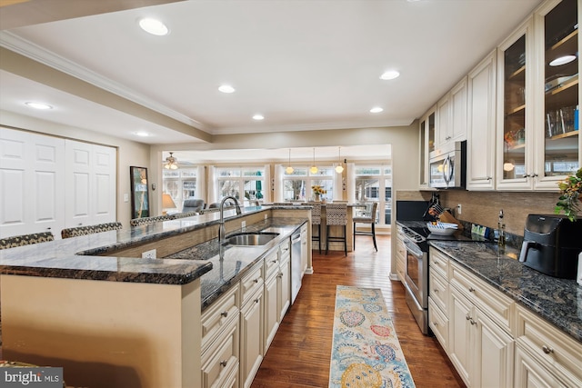 kitchen featuring a large island, sink, dark wood-type flooring, dark stone counters, and stainless steel appliances