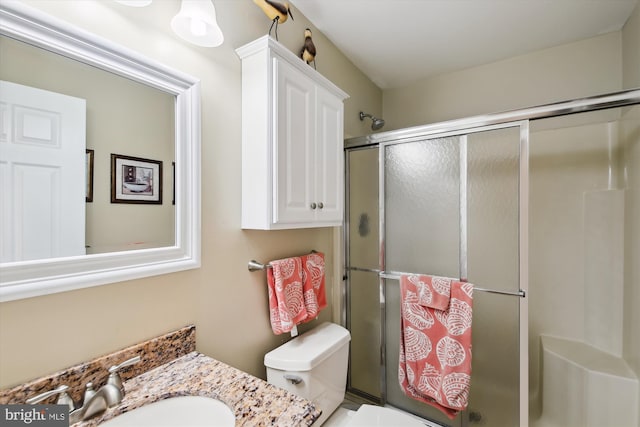 bathroom featuring toilet, a shower with shower door, and vanity